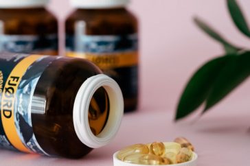 Close-up of omega-3 capsules and bottles on a pink background, ideal for health and wellness themes.