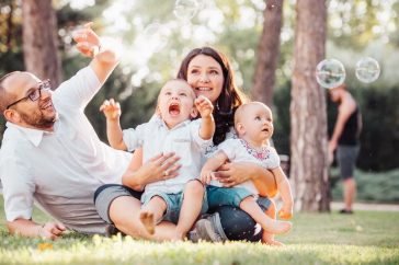 Joyful family enjoying a sunny day in the park while playing with bubbles.